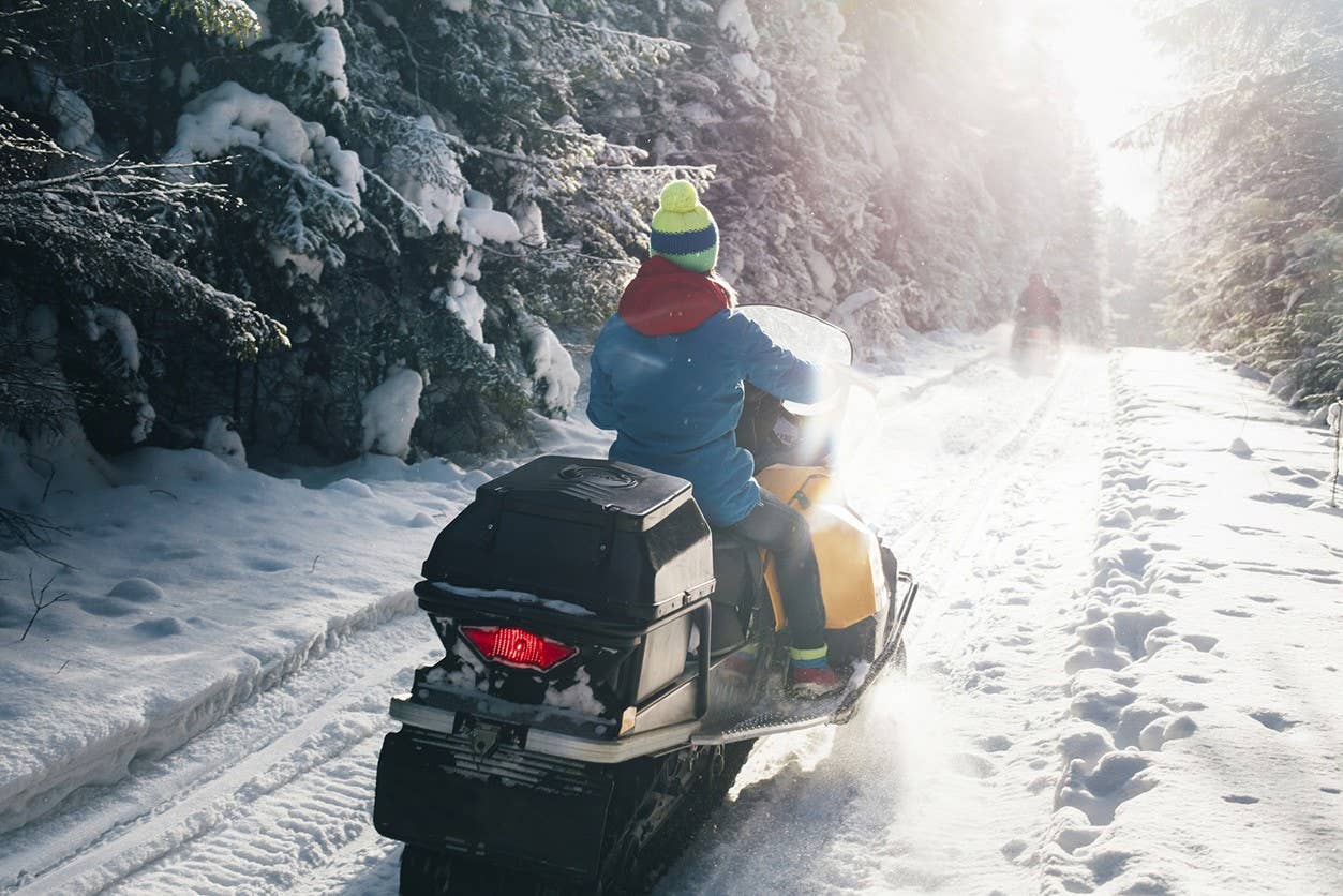 A woman riding a snowmobile in the middle of wyoming.