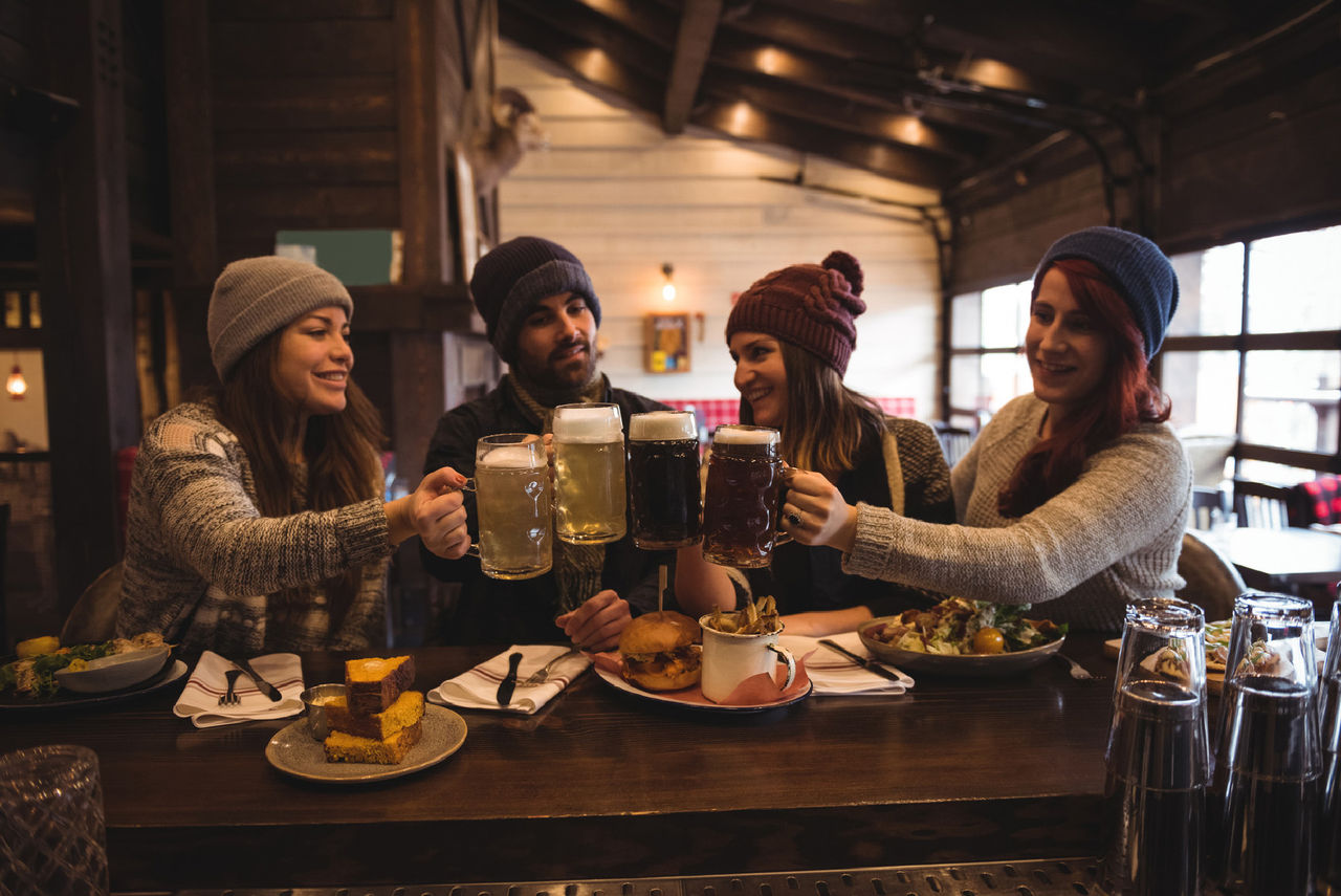 Friends toasting with beer glasses in bar